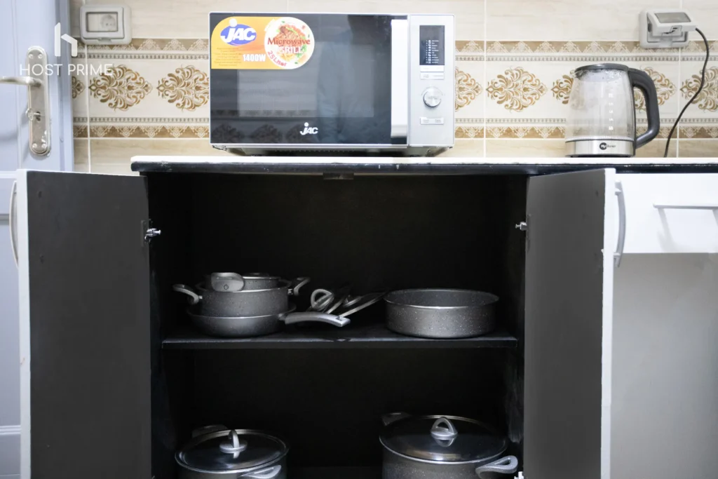 A modern kitchen with a fridge, a stove, and a microwave in a bright 2-bedroom apartment in New Cairo