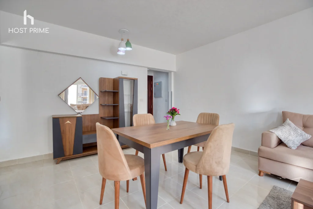 A bright and airy living room with a sofa, a coffee table, and a TV in a Host Prime serviced apartment in New Cairo