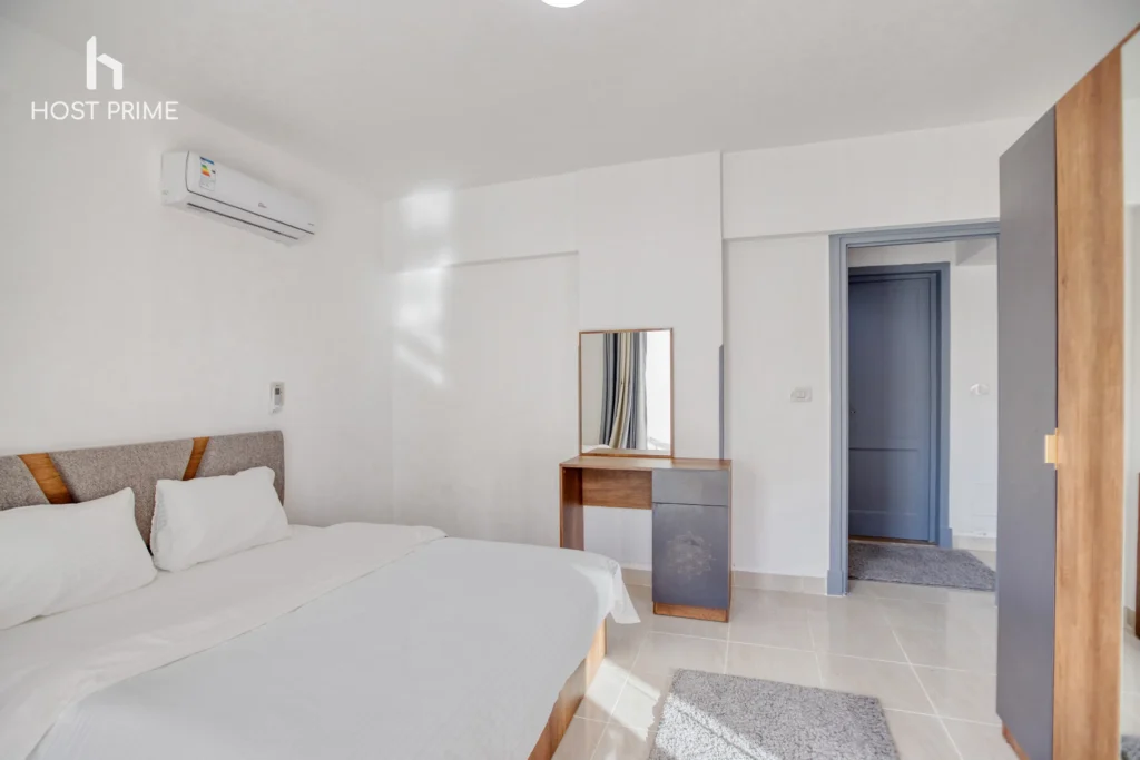 A cozy bedroom with a king-sized bed, a nightstand, and a lamp in a Host Prime accommodation in New Cairo