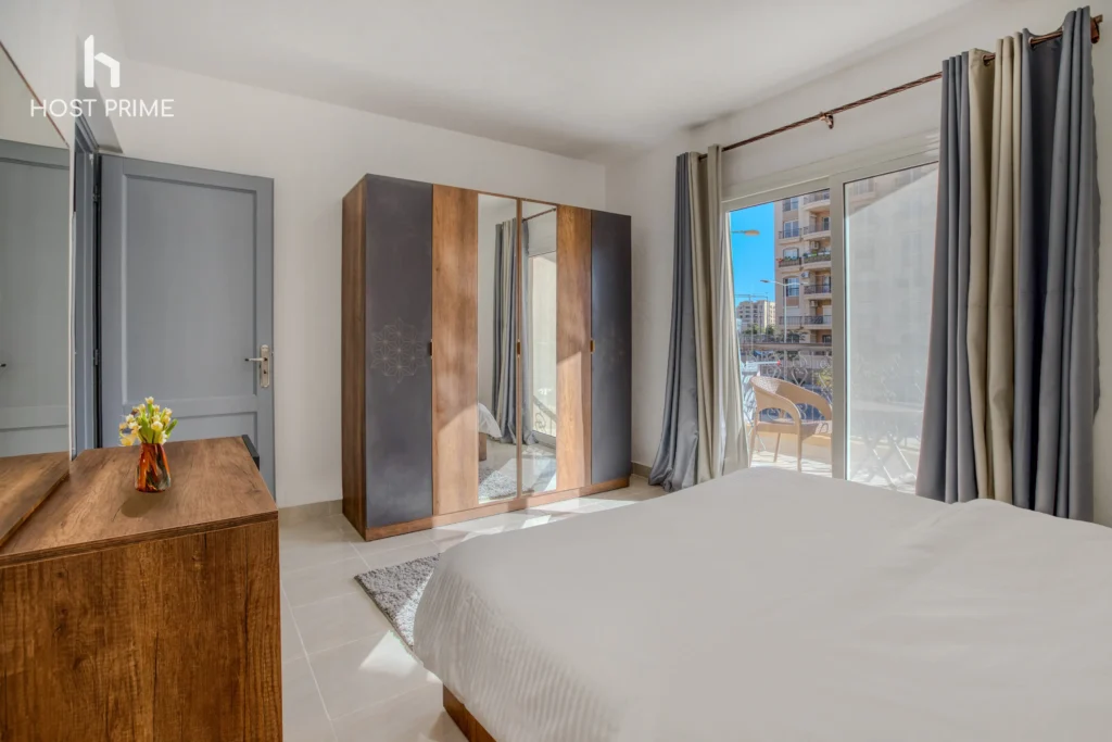 A balcony with a view of the city and a table with chairs in a bright 2-bedroom apartment in New Cairo