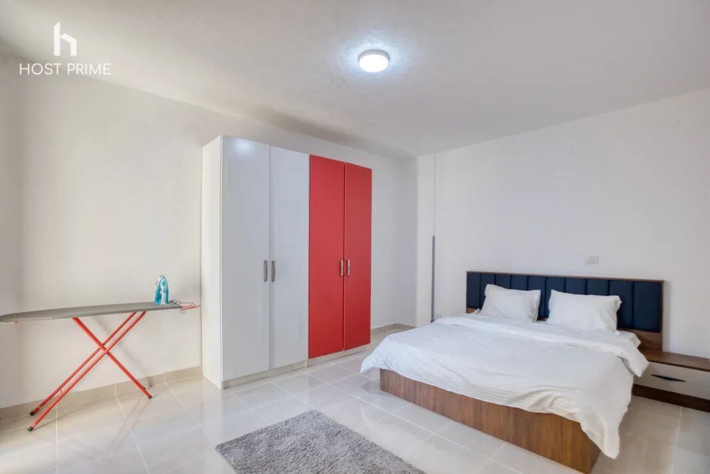 A cozy bedroom with a queen-sized bed, a nightstand, and a lamp in a Host Prime accommodation in New Cairo
