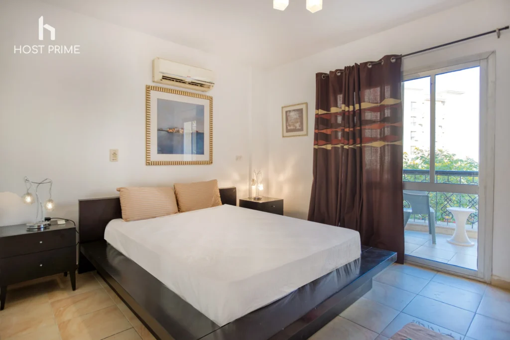 A cozy bedroom with a queen-sized bed, a nightstand, and a lamp in a Host Prime accommodation in Cairo
