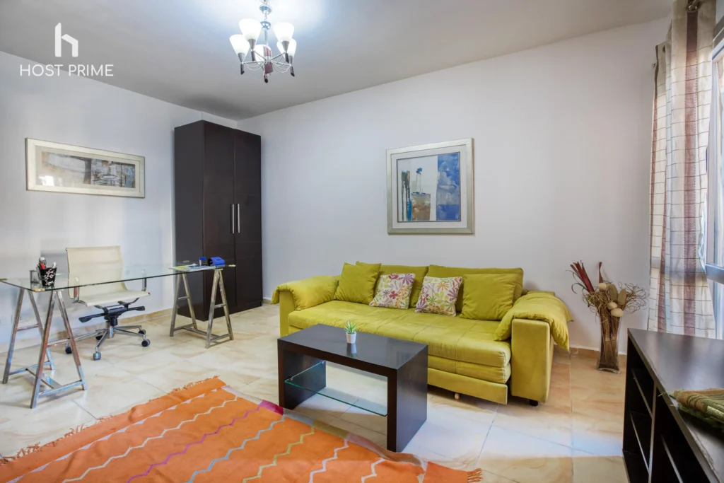 A comfortable living room with a sofa, a coffee table, and a TV in a Host Prime serviced apartment in Cairo